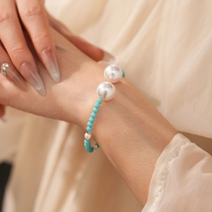 Gros plan d'un bracelet en perles et turquoise au poignet sur un fond chaud minimaliste