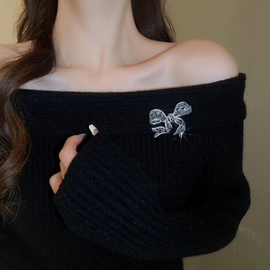 Detailed view of a crystal bow brooch with purple and green stones on a black sweater