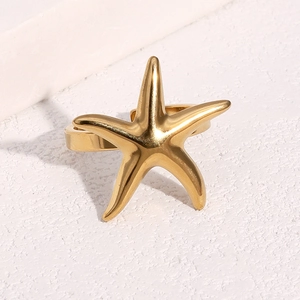 Starfish shaped 18k gold plated stainless steel open ring on a textured white pedestal