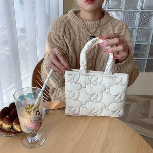 Detail of soft quilted cream handbag with cute rabbit patterns for casual daily use