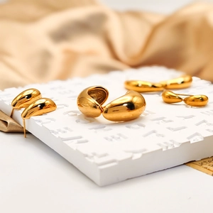Golden teardrop and bean shaped stainless steel stud earrings set on a pedestal