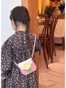 Close-up of a handmade crochet mini bag with floral patterns on a child model back