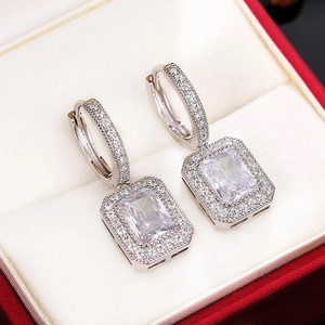 Macro detail showing rectangular cut moissanite drop earrings with sparkling halo setting