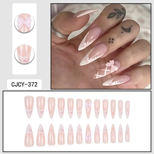 Pink almond press-on nails with white French tips, lace patterns and 3D bows