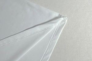 Close-up of double-stitch sewing and knit fabric texture on white maxi dress hem