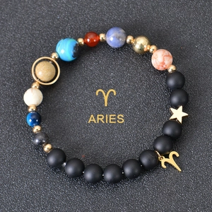 Detail of Aries zodiac charm with colorful planetary beads on a matte black stone bracelet