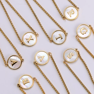 Macro shot of 18k gold plated round shell pendants featuring elegant A-Z alphabet initials