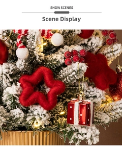 Detail of snow-flocked pine branch with red stars, gift box ornaments, and warm LED lights