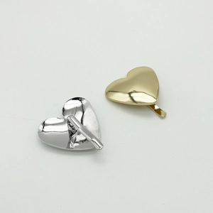 Close-up of sleek gold and silver heart-shaped metal hair clips with a polished finish