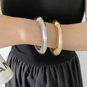 Gros plan sur un bracelet épais minimaliste poli brillant aux finitions dorées et argentées