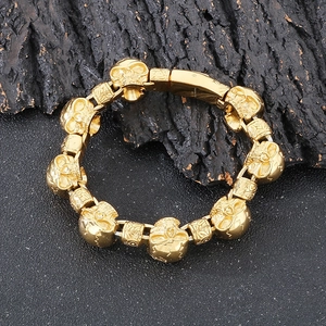 Detailed close-up of golden punk skull bracelet link on dark textured surface