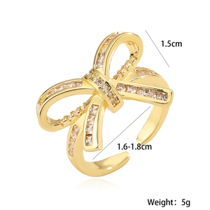 Gold hollow bow ring with 18K plating and sparkling zircons on white background