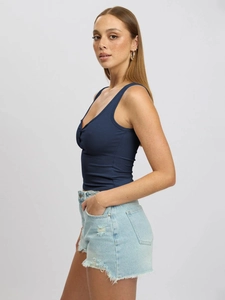 Detailed close-up of dark blue ribbed tank top and light blue frayed denim shorts