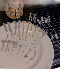 Close-up of bow tassel earrings with sparkling rhinestones and pearl accents in a ceramic tray