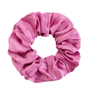 Detailed view of fuchsia satin scrunchie showing glossy fabric texture and elastic pleats