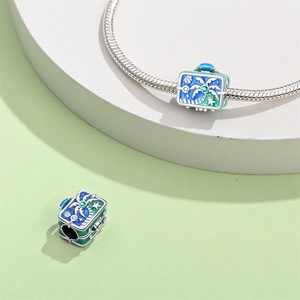 Detail of silver suitcase charm with enamel coconut trees on snake chain bracelet