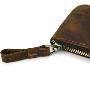 Close-up of genuine dark brown leather coin pouch with bronze metal zipper and hand-stitched detail