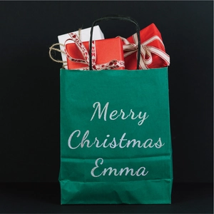 Close-up of green Christmas gift bag with glitter Merry Christmas Emma lettering