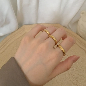 Three-piece minimalist gold stainless steel band rings set on hand with stone tray