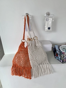 Detail of bohemian woven tassel bags with wooden handles in orange and beige colors