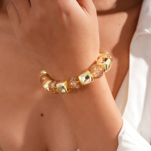 Detail of amber beads and golden square metal beads on a vintage acrylic beaded bracelet