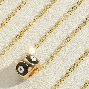 Macro shot of gold evil eye pendant necklace with black and white enamel finish