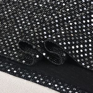Détail du tissu en maille noire avec paillettes argentées scintillantes sur la robe