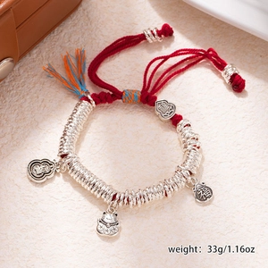 Detail view of red braided bracelet with silver charms including lucky cat and gourd