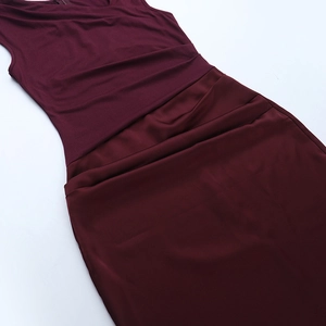 Detail of burgundy ruched sleeveless dress showing smooth satin texture and elegant pleats