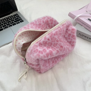Detailed view of pink leopard print plush makeup bag on a desk with laptop