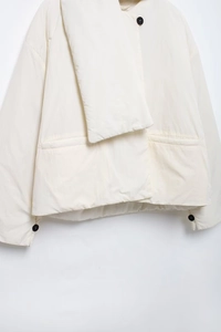 Detailansicht der weißen minimalistischen Steppjacke mit schwarzen Knöpfen und Reverskragen