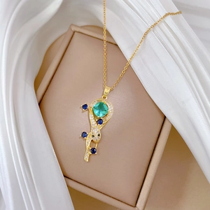 Close-up of a luxury gold snake necklace featuring a green stone and blue crystals