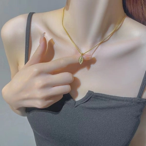 Elegant gold leaf pendant necklace with fine texture worn by a model in soft natural light