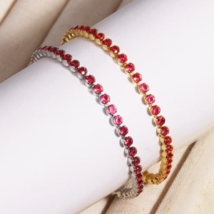 Elegant gold and silver tennis bracelets with red zircon crystals on a white pedestal