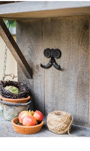 Detail van een vintage gietijzeren wandhaak in snorvorm op een rustieke houten wand