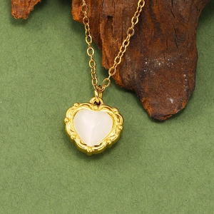 Détail du collier pendentif cœur en opale avec cadre doré évidé sur fond sombre