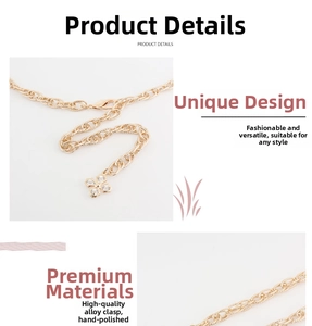 Detail of gold chain belt featuring a lobster clasp and rhinestone floral clover pendant