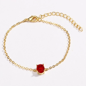 Close-up of a gold-plated bracelet with an oval red zircon stone and lobster clasp