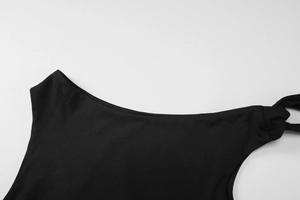 Detail eines schwarzen Off-Shoulder-Tops mit asymmetrischem Ausschnitt und Schulterknoten