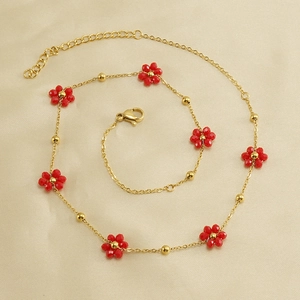 Detail of golden stainless steel necklace with red flower beads and lobster clasp