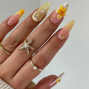 Detailed macro of 3D lemon and seashell nail art with gold starfish accessories