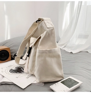 Vue détaillée du sac bandoulière en toile crème montrant la boucle noire et la poche