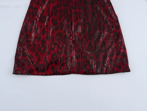 Détails de sequins léopard rouges et noirs sur une mini-jupe moulante de fête