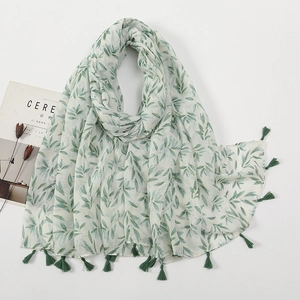 Detail of white cotton linen scarf featuring green leaf prints and fringe tassels