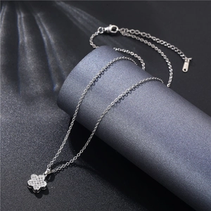 Close-up of silver flower pendant necklace with zircon stones on a gray display stand