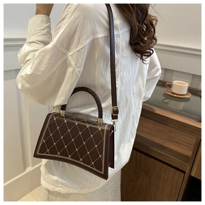 Close-up of brown quilted handbag with star pattern embroidery and woven handle detail