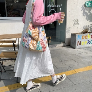 Detail of canvas tote bag with vibrant colored stripes in a cozy outdoor cafe setting