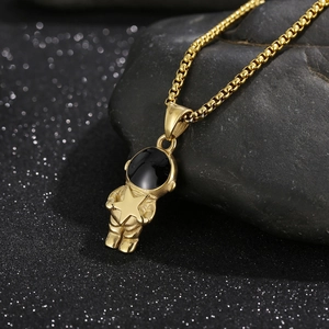 Detail shot of a golden astronaut pendant holding a star on a sleek black box chain