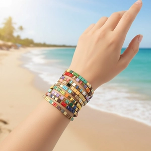 Close-up of bohemian colorful TILA bead bracelets stacked on wrist with beach background
