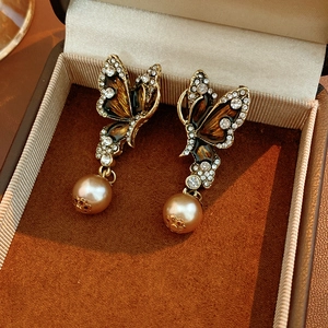 Close-up of vintage butterfly earrings with brown enamel, rhinestones and pearls